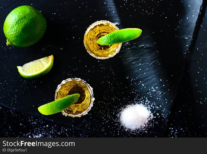 Mexican Gold Tequila with lime and salt on stone bar counter, flat lay, top view.