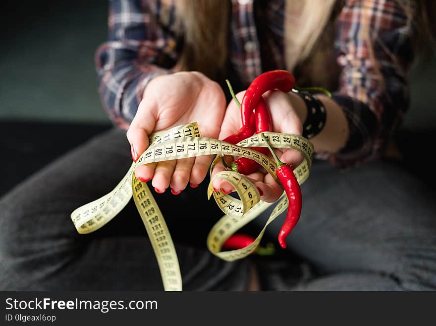 Vegetarian food lifestyle. healthy eating habits. fresh organic vegetable for slimming and weightloss. woman holding fresh chili pepper with twisted measuring tape in hand. Vegetarian food lifestyle. healthy eating habits. fresh organic vegetable for slimming and weightloss. woman holding fresh chili pepper with twisted measuring tape in hand.