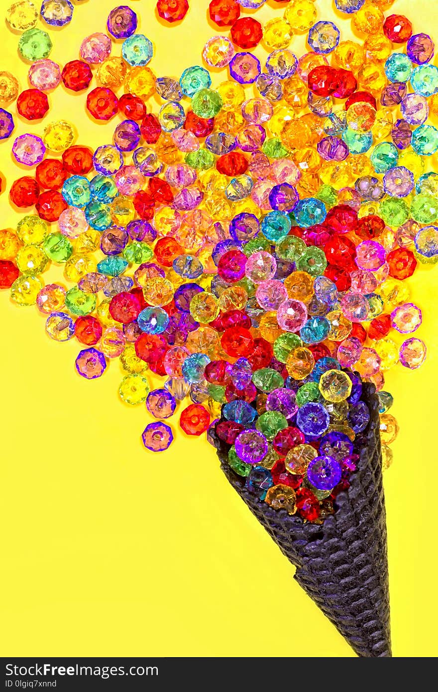 Ice cream cone with multicolored beads on a yellow background