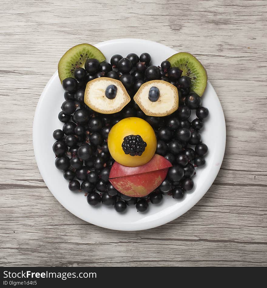 Bear made with currant, apple, kiwi and banana. Funy idea for making decorative figure from fruits. Shot on wooden background. Bear made with currant, apple, kiwi and banana. Funy idea for making decorative figure from fruits. Shot on wooden background.