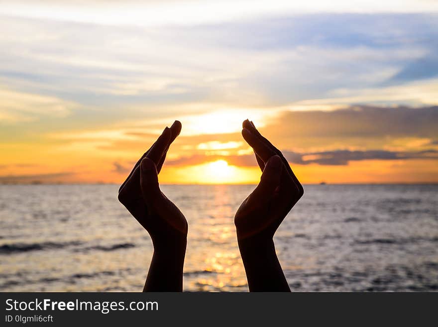 Woman hands holding the sun during sunrise or sunset.