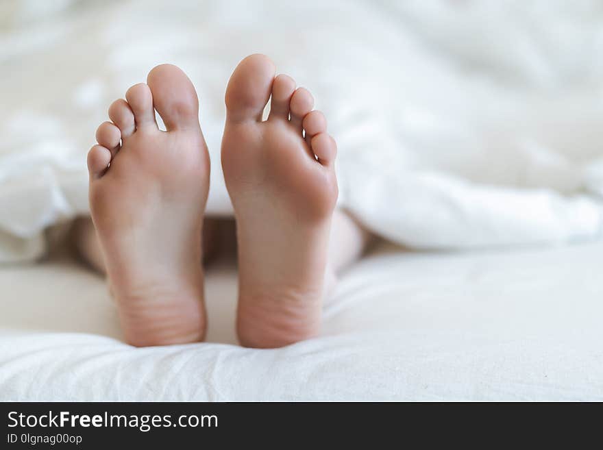 Close up of two feet in a bed.