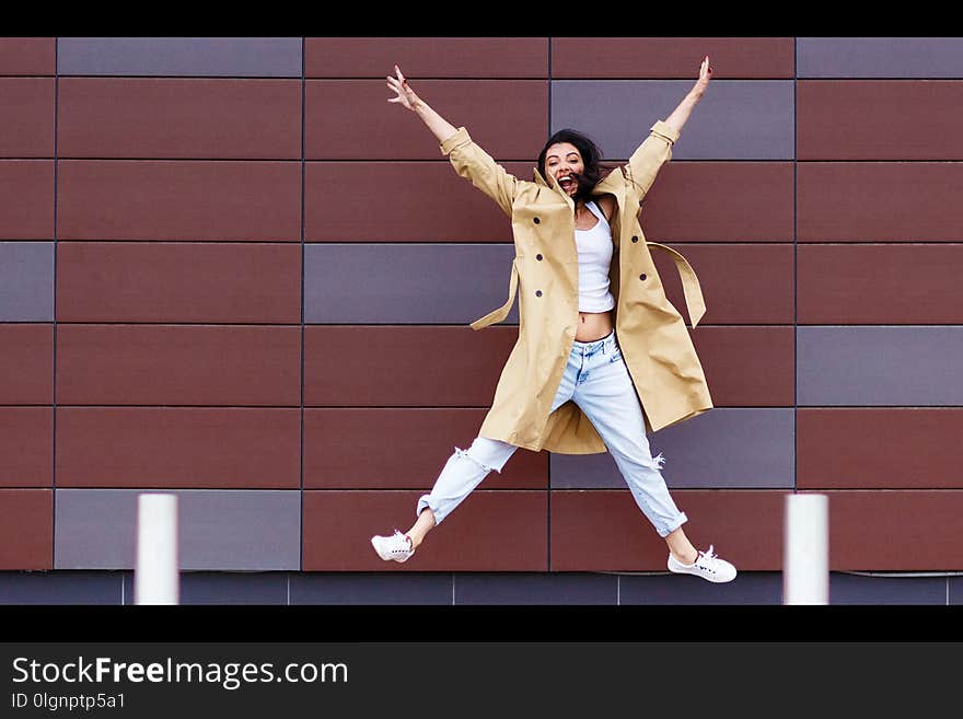 Beautiful woman in the beige coat and jeans on the street