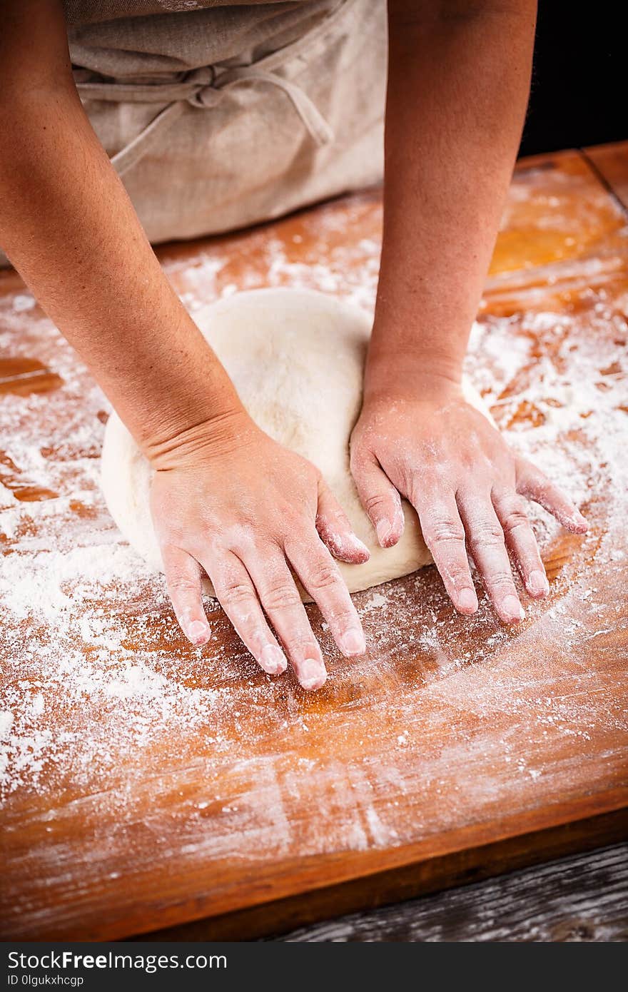 Woman`s hands knead dough on a table