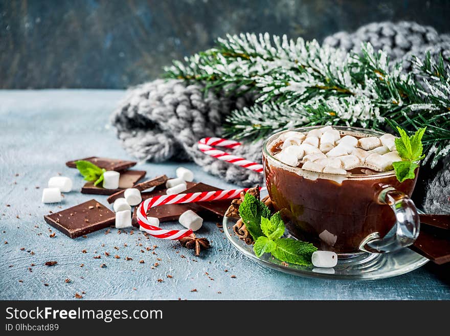 Homemade hot chocolate with mint, candy cane and marshmallow, light blue background with warm blanket, copy space. Homemade hot chocolate with mint, candy cane and marshmallow, light blue background with warm blanket, copy space