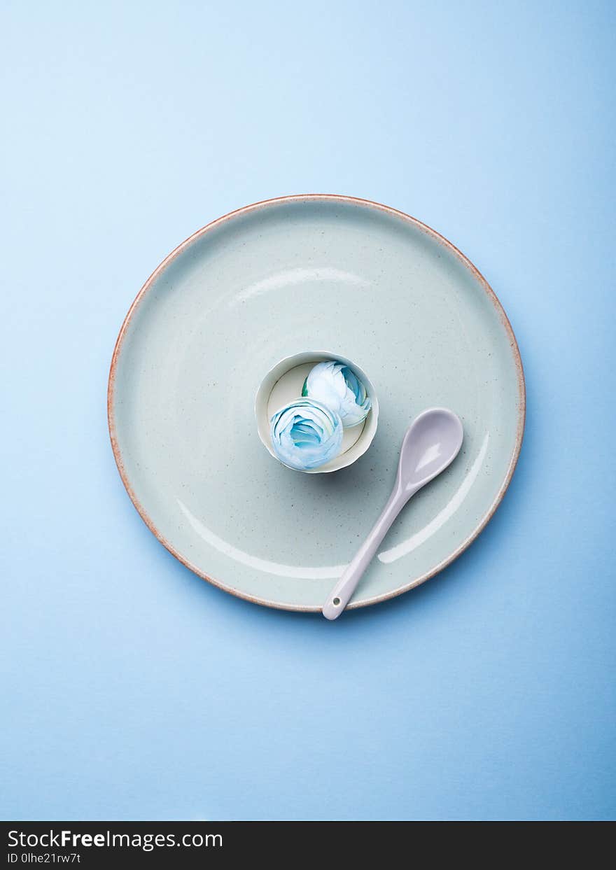 Blue pastel ceramic dish with flowers and spoon. Abstract food, tableware crockery, table setting monochrome concept