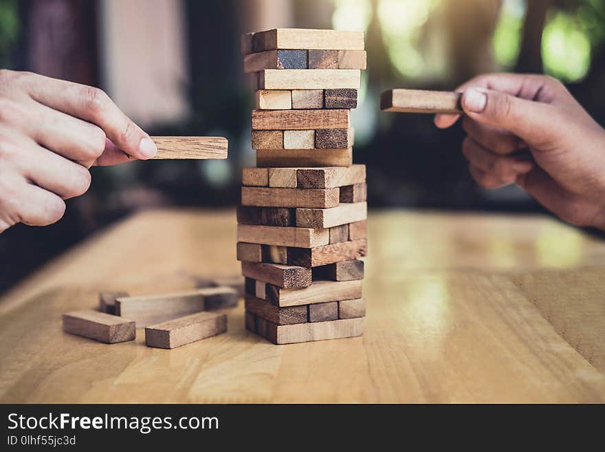 Hands of executive cooperation placing wood block on the tower, Collaborative management, Young intelligent businessman playing the wood game, Alternative risk concept, plan and strategy in business.