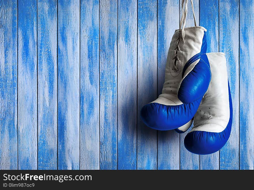 Blue boxing gloves on a blue wooden background. Blue boxing gloves on a blue wooden background.