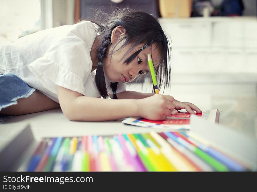 Asian children playing and painting color pencil on paper book in home school