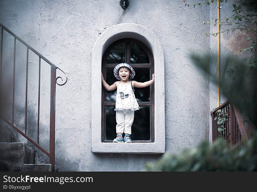 Happy cute little girl smiling and standing by the window with vintage color tone.