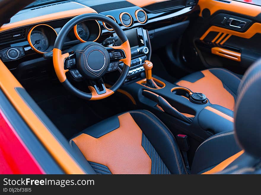 Sports car interior with orange accents. Horizontally framed shot.