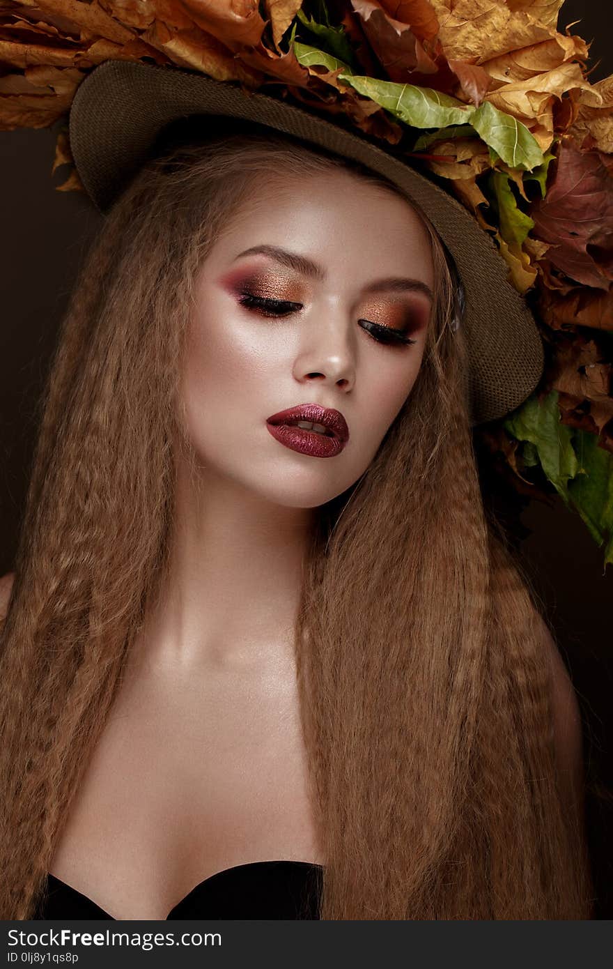 Beautiful blond model in autumn hat : curls, bright makeup, red lips. The beauty face.