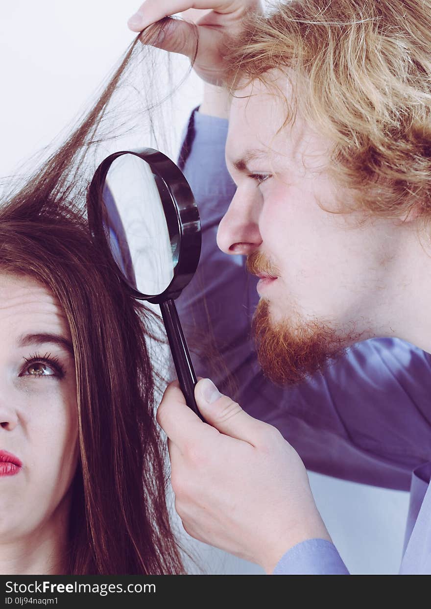 Man looking at women hair roots using magnifying glass. Guy having doubts about trichology. Man looking at women hair roots using magnifying glass. Guy having doubts about trichology