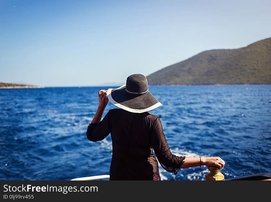 Beautiful girl in hat relaxing on the boat and looking at the island. Travelling vocation tour in Turkey