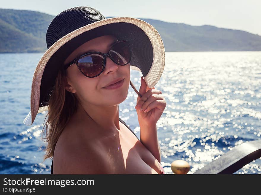 Beautiful girl in hat relaxing on the boat and looking at the island. Travelling vocation tour in Turkey