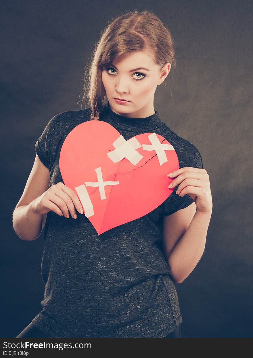 Heart broken concept. Sad unhappy blonde woman with big red love sign symbol glued by plaster. Girlfriend in valentines day. Filtered. Heart broken concept. Sad unhappy blonde woman with big red love sign symbol glued by plaster. Girlfriend in valentines day. Filtered.