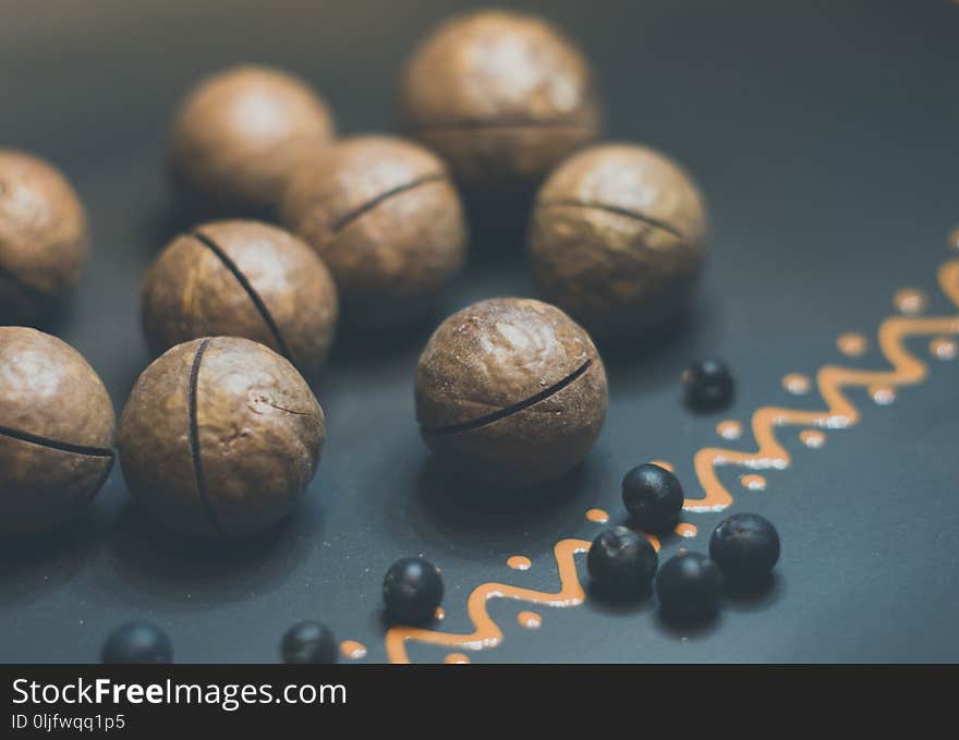 macadamia, Australian nut and juniper berries in a ceramic plate on a wooden table, close-up, toned. macadamia, Australian nut and juniper berries in a ceramic plate on a wooden table, close-up, toned