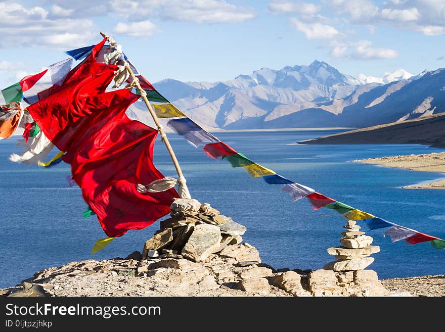 Buddhist prayer flags on the wind against the blue lake, mountains and sky