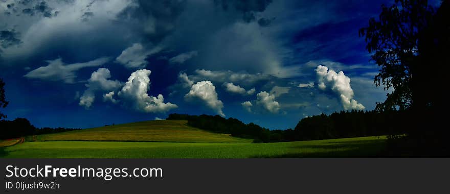 Scenic landscape with storm cloud in background over green agriculture fields