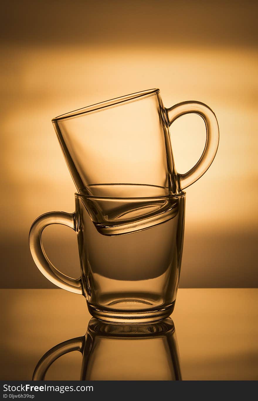 Two glass cups on an orange background.