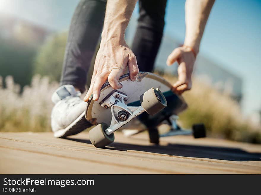 Close up of young attractive man riding longboard in the park. Man is on foreground, park is on background.