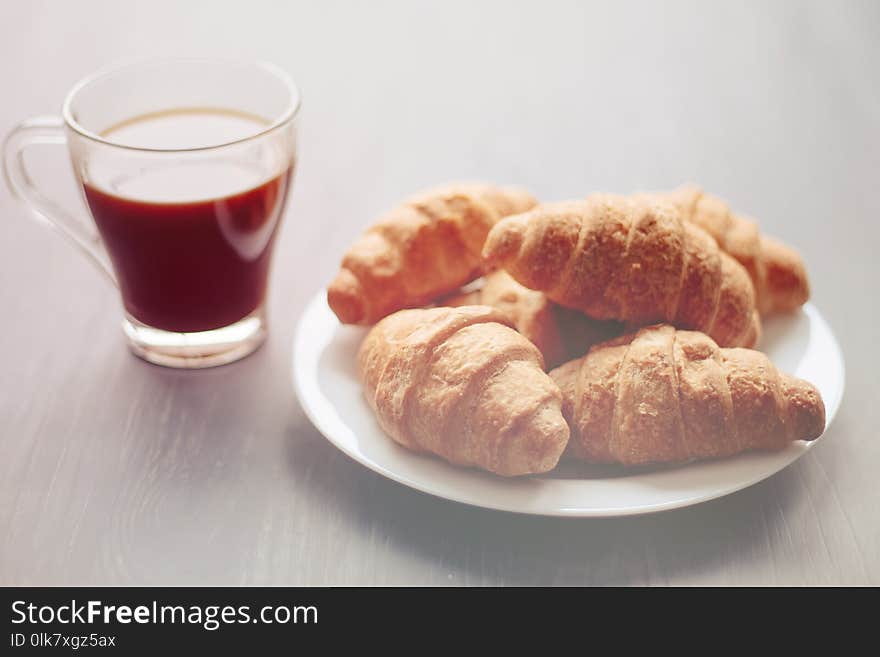 Coffee cup and fresh baked croissants on wooden background. Top View, light toning