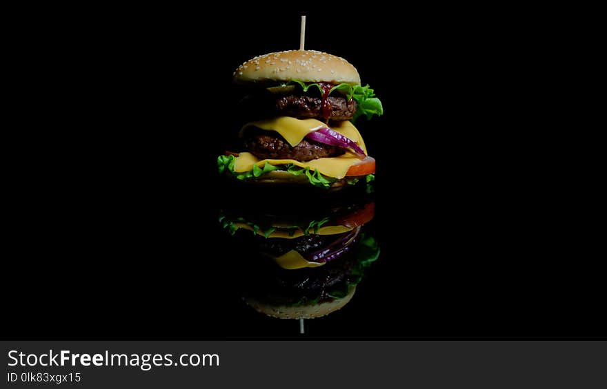 Tasty burger with beef, cheese and greens on the black glass background for commercial. Tasty burger with beef, cheese and greens on the black glass background for commercial