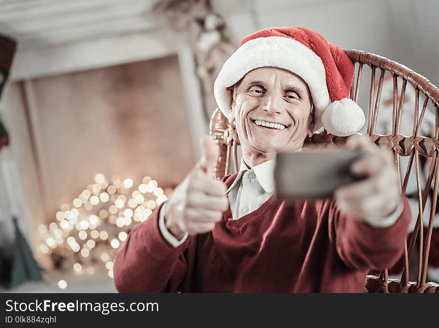 Video call. Happy male keeping smile on his face and stretching hand while looking at camera. Video call. Happy male keeping smile on his face and stretching hand while looking at camera