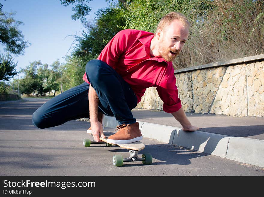 Skater in red shirt and blue jeans riding near beach on longboard during sunrise, sea or ocean background. Skater in red shirt and blue jeans riding near beach on longboard during sunrise, sea or ocean background