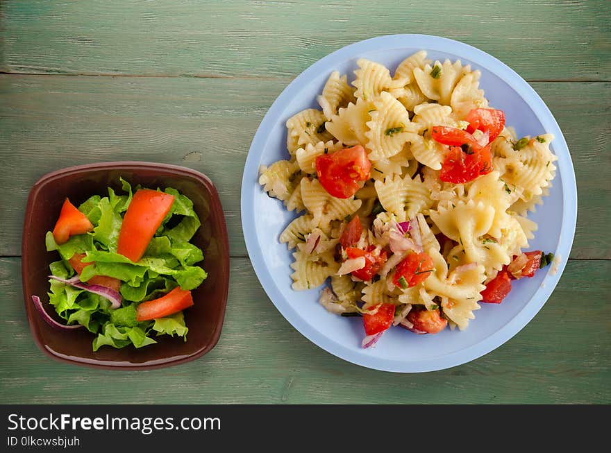 Pasta on a plate. pasta tomatoes, onions, cabbage on a wooden background