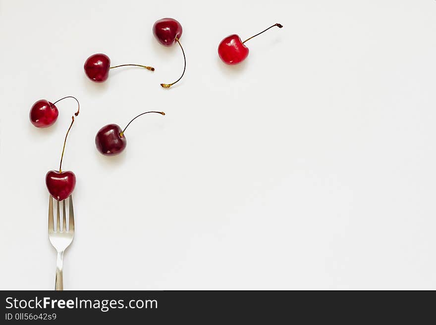 Red cherry fruits and fork on white background with copy space for text. Summer, diet, healthy food eating consept. Top view, flat lay, layout, pattern