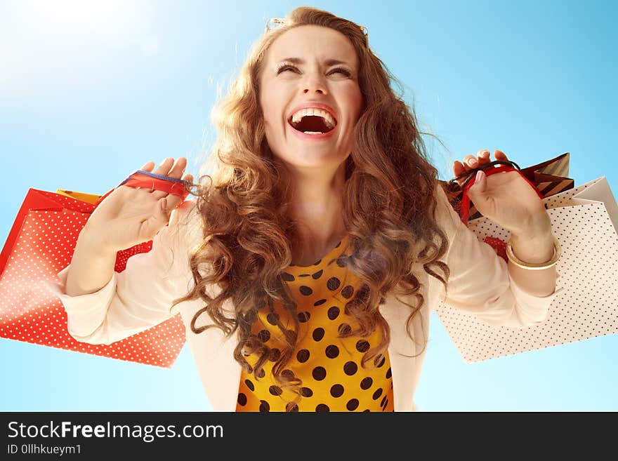 Happy woman with shopping bags rejoicing against blue sky