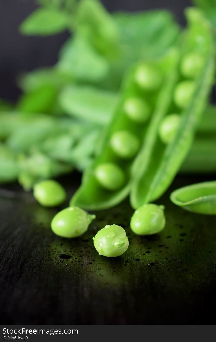 Green pea pods against the dark background