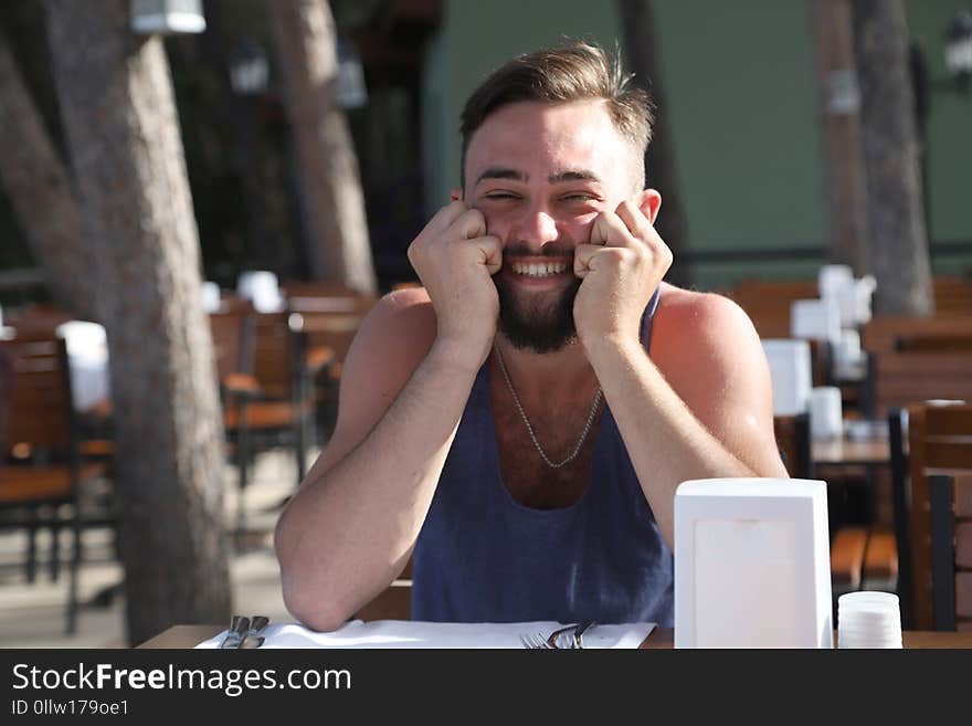 Young man with black hair and beard sitting in a restaurant in the Park in a summer evening