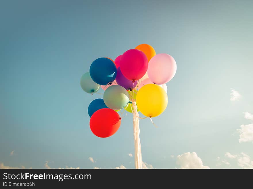 Colorful festive balloons over blue sky with a retro vintage instagram filter effect.