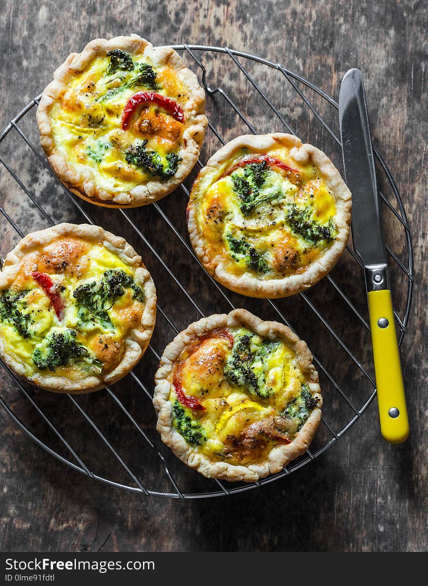 Broccoli cheddar mini savory pies on wooden background, top view. Delicious appetizers, snack, tapas. Flat lay