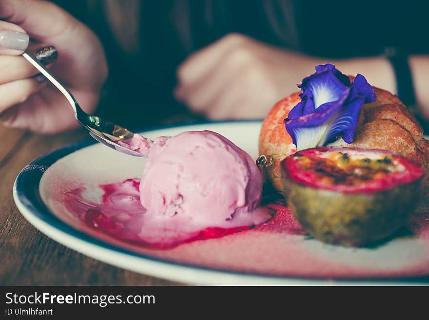 Closeup image of woman eating a dish of Choux cream , rose ice-cream and passion fruit with beautiful decoration