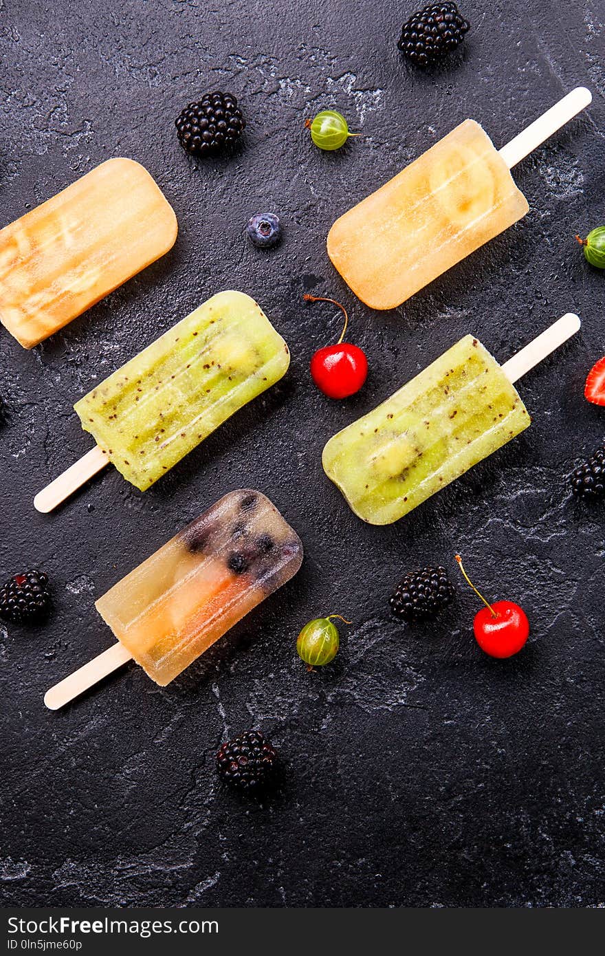 Photo of ice cream on stick,blackberry, cherry, gooseberry on black background. Photo of ice cream on stick,blackberry, cherry, gooseberry on black background