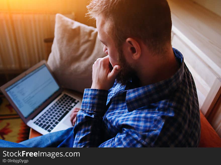 Young man working with computer on the beach. Handsome man working with laptop laying on the couch at the beach.