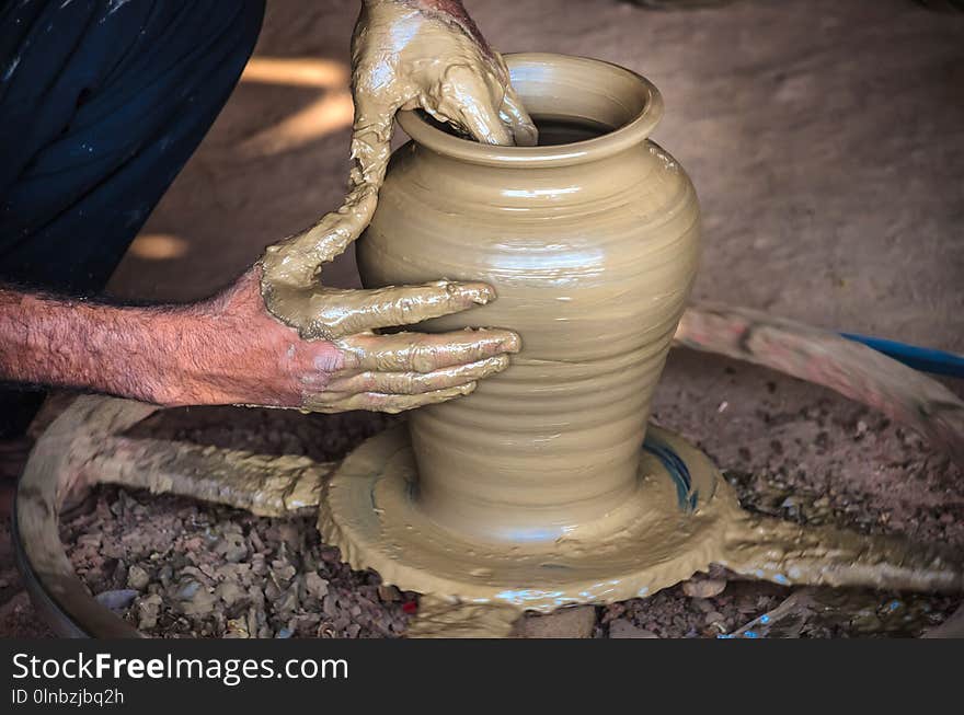 Closeup of potter`s hands making clay water pot on pottery wheel.