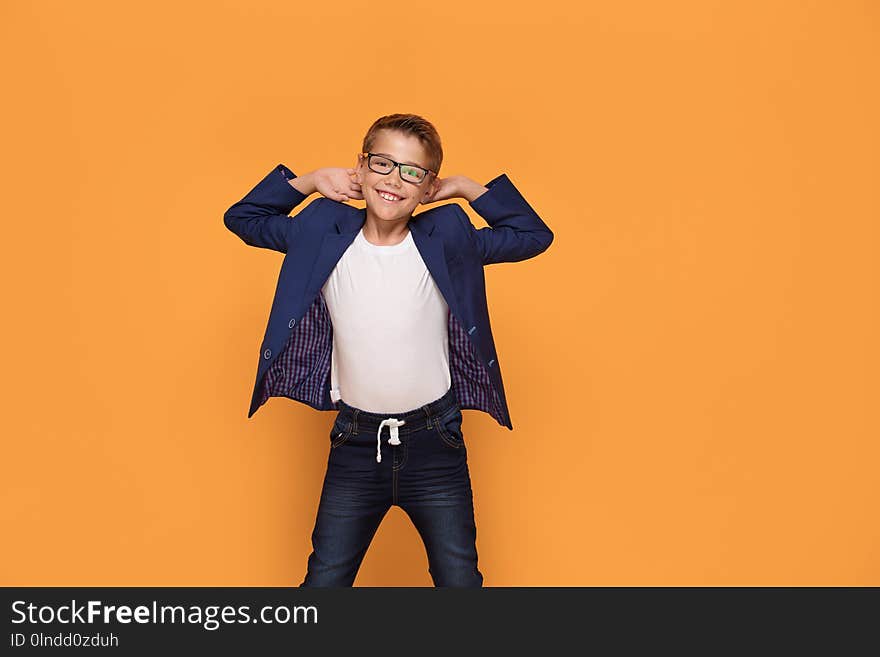 Smiling happy little elegant boy posing on orange studio backgroud, wearing fashionable eyeglasses and jacket. Smiling happy little elegant boy posing on orange studio backgroud, wearing fashionable eyeglasses and jacket.