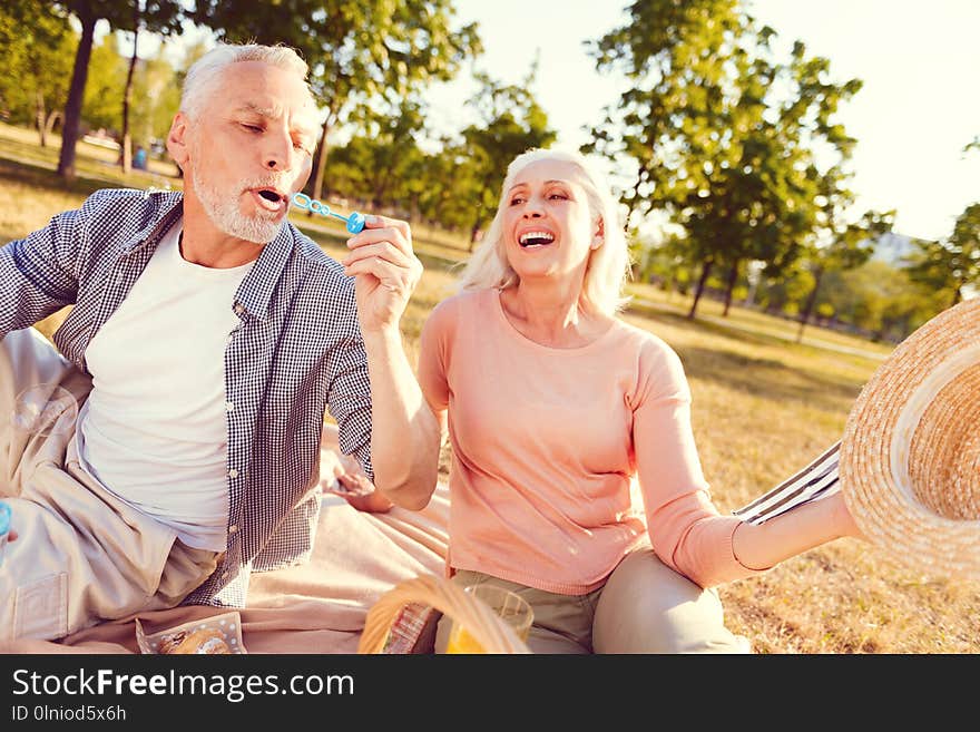 Extremely happy wife looking at husband blowing soap bubbles