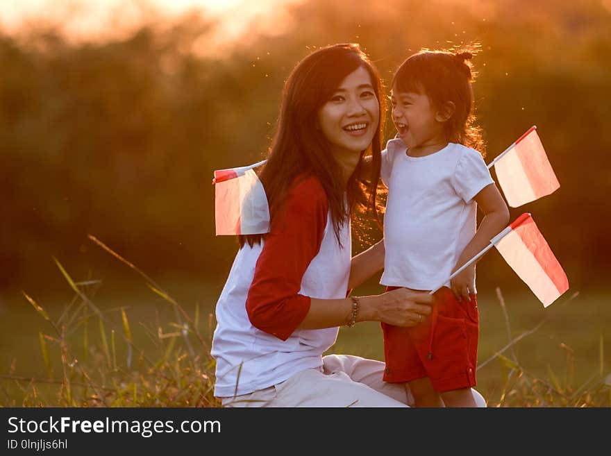 Mother and daughter raising flag of indonesia