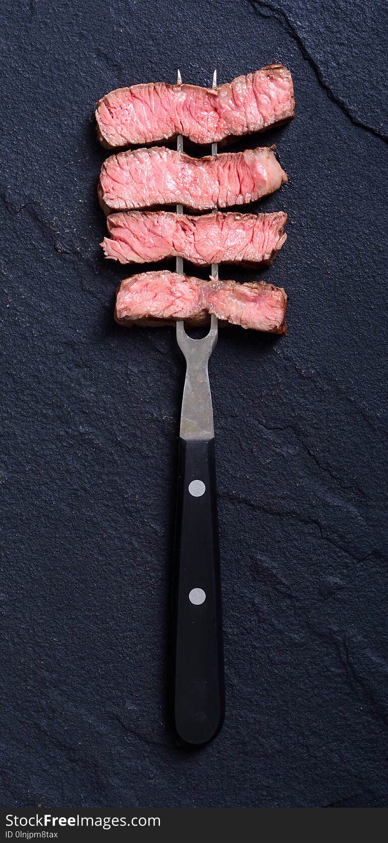 Grilled beef steak ribeye on meat fork sliced