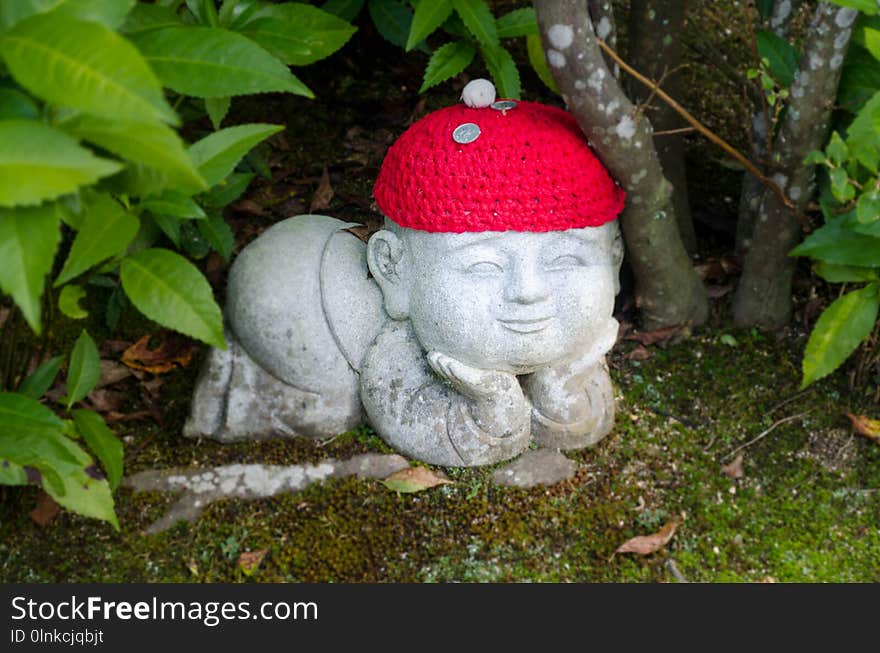 Stone child with two coins on top of his red beret. Daisho in temple. Stone child with two coins on top of his red beret. Daisho in temple