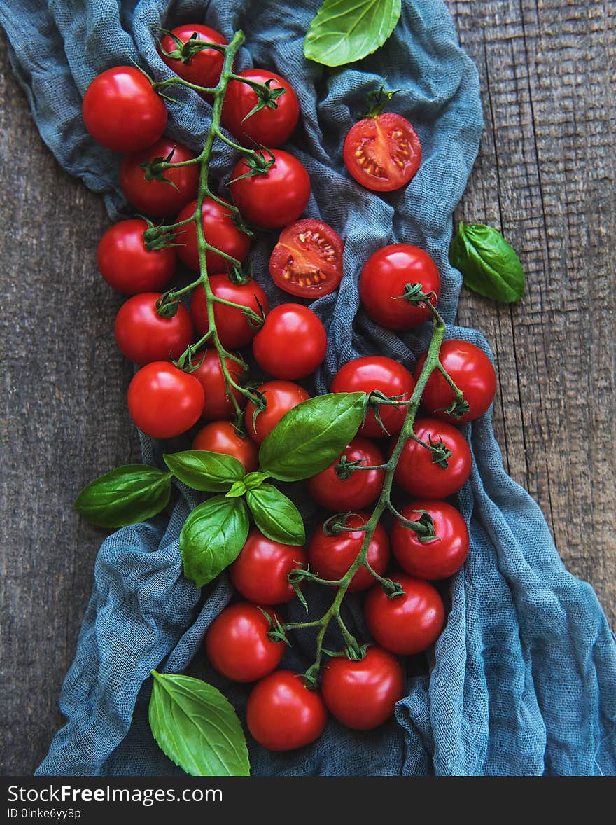 Fresh cherry tomatoes and basil leaves on a old wooden background