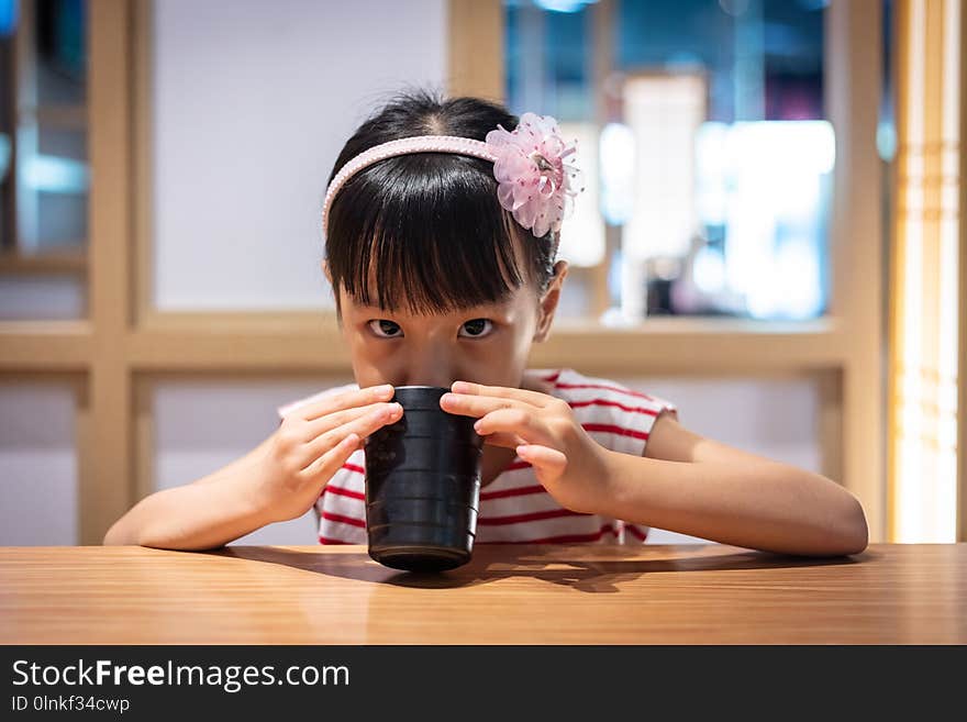 Asian little Chinese girl drinking hot green tea at a Japanese restaurant