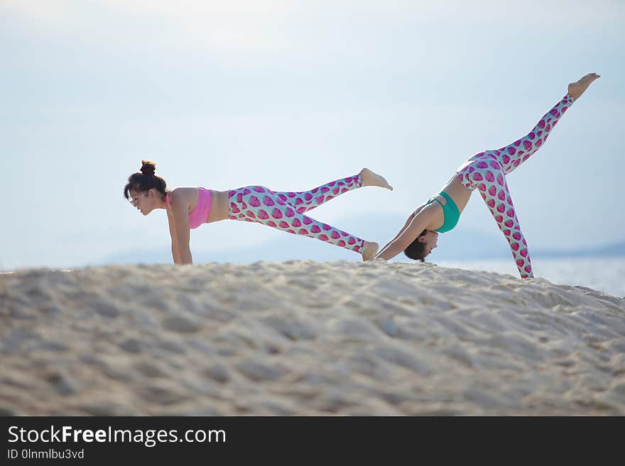 Two woman playing yoga pose on sea beach