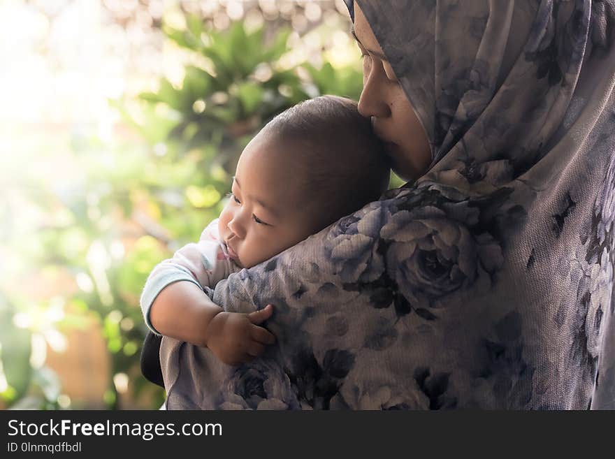 A Muslim mother from Indonesia wearing hijab holding her baby daughter. A Muslim mother from Indonesia wearing hijab holding her baby daughter