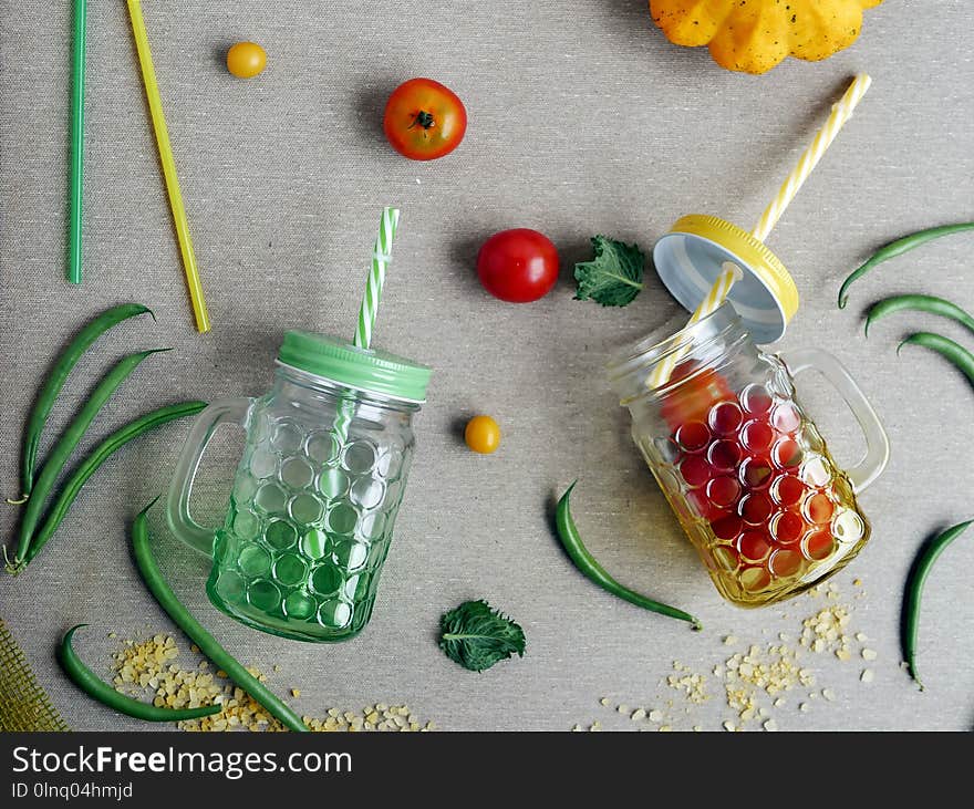 Decorative seasonal composition of tomato and asparagus beans, fresh cups and cocktail tubes on a gray light background, top view